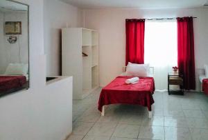 a bedroom with a bed with a red blanket and a window at RedDoorz at Rio Bella Lacson St Bacolod in Bacolod
