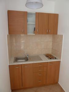 Una cocina con fregadero y armarios de madera. en Rose Apartments, en Ičići 2 fotos más