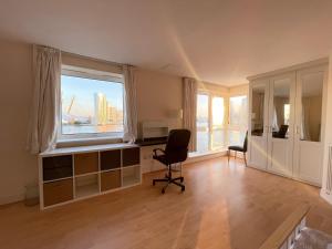 Very large ensuite room with wonderful view over the river Thames in a peaceful & calm residential building - SHARED flat with 1 host في لندن: غرفة بها مكتب وكرسي ونافذة