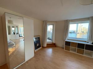 a living room with a mirror and a large window at Very large ensuite room with wonderful view over the river Thames in a peaceful & calm residential building - SHARED flat with 1 host in London