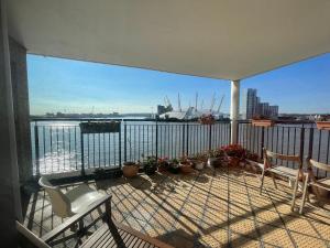 a balcony with chairs and a view of the water at Very large ensuite room with wonderful view over the river Thames in a peaceful & calm residential building - SHARED flat with 1 host in London