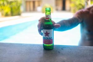 uma pessoa segurando uma garrafa de cerveja em uma mesa em Castaway Island Hostel em Nusa Lembongan