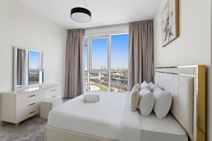 a white bedroom with a white bed and large windows at Spacious 1BR APT Wasl in Dubai