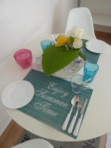 a table with a green place mat and a vase of flowers at Rose Apartments in Ičići