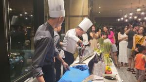 un grupo de personas de pie alrededor de una mesa con un chef en Apec Mandala Phú Yên, en Tuy Hoa