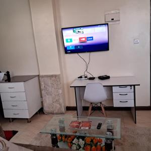 een kamer met een bureau en een tv aan de muur bij Ngara - Emeli in Nairobi