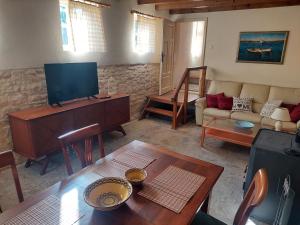 ein Wohnzimmer mit einem TV und einem Sofa in der Unterkunft Къщи за гости Мечта in Poroishte