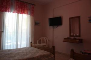 a bedroom with a bed and a television and a chair at Sunray Studios Stavros in Stavros