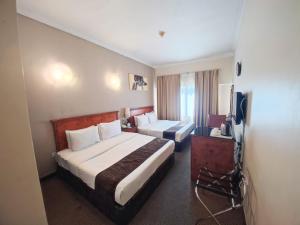 um quarto de hotel com duas camas e uma televisão em Nejoum Al Emarat em Sharjah