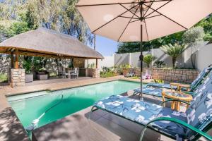 a swimming pool with chairs and an umbrella at 76 On Crestwood in Sandton