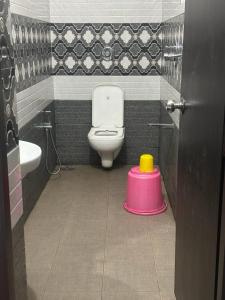 a bathroom with a toilet and a pink stool at Kosher Livings in Kalpetta