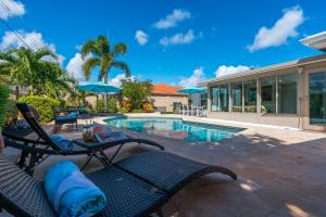 a pool with two chairs and a table next to a house at Grand Pool Villa Minutes to the Beach! Sleeps 8! in Boynton Beach