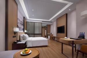 Habitación de hotel con cama blanca y escritorio en Metropark Hotel Wuhan, en Wuhan