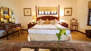 a bedroom with a large bed and a desk at Ursula's Homestead in Victoria Falls