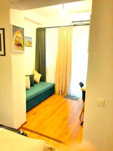 Hotel Art Nikola Rooms في تبليسي: غرفة معيشة مع أريكة خضراء أمام نافذة
