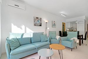 a living room with a blue couch and two chairs at Brisas C2 in Pedreguer