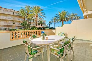 a white table and chairs on a balcony with palm trees at Brisas C2 in Pedreguer