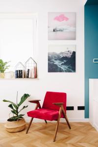 una silla roja en una habitación con una planta en Bochenka Apartments, en Cracovia