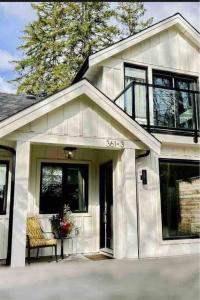 a white house with a front door and a chair at New Private West Coast Guesthouse on the creek in North Vancouver