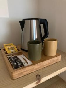 Résidence Thibaud في تولوز: وعاء القهوة وكوبين على صينية خشبية