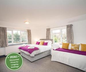 1 Schlafzimmer mit 2 Betten mit lila und gelben Kissen in der Unterkunft OYO Wilson Lodge in Maidenhead