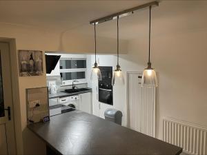 a kitchen with three lights hanging over a counter at The Ironstone Miners Cottage in Wilton