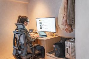 a woman sitting at a desk with a laptop computer at 脈 -MYAKU PRIVATE SAUNA- in Fukuoka