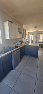 a large kitchen with white cabinets and blue counters at Quaint Family home, walking distance to the beach in Cape Town