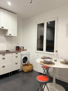 eine weiße Küche mit einem Tisch und einer Waschmaschine in der Unterkunft Maison Paisible à 15 min de Disneyland ! in Crégy-lès-Meaux