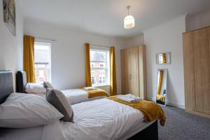 a bedroom with two beds and a window at Inspired Stays- City Centre- Spacious 4 Bed House! in Stoke on Trent