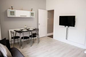 a living room with a table with chairs and a tv at Inspired Stays- Close to City Centre- 4 Bed House! in Ford Green