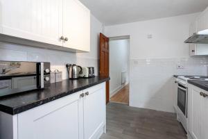 a kitchen with white cabinets and a black counter top at Inspired Stays- City Centre- Spacious 4 Bed House! in Stoke on Trent