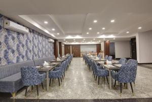 um restaurante com mesas longas e cadeiras azuis em Hotel La Mirage em Noida