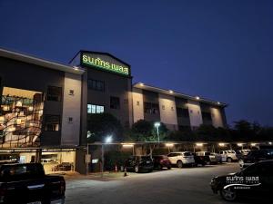 un edificio con coches estacionados en un estacionamiento en Thanaphat place, en Buriram