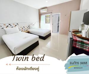 a hotel room with two beds and a television at Thanaphat place in Buriram
