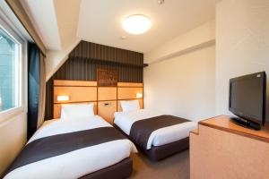a hotel room with two beds and a flat screen tv at Hotel Villa Fontaine Tokyo-Hamamatsucho in Tokyo