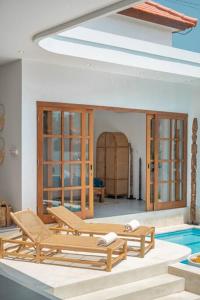 una piscina con 2 sedie a sdraio e una piscina di CASA BIARI : Tropical Vibes - 3 min from beach a Canggu