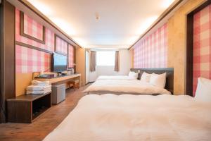 台中市にある台中灣文旅 T C ONE Hotelのベッド2台とテレビが備わるホテルルームです。