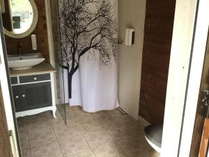 a bathroom with a tree painted on the wall at Treehouse Čiekurs in Duķuri