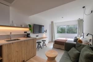 a living room with a couch and a kitchen and a bed at Cabot Las Velas Apartments in Port de Pollensa