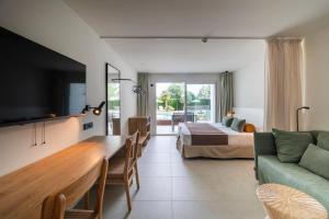 a hotel room with a bed and a couch and a table at Cabot Las Velas Apartments in Port de Pollensa