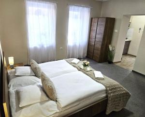 a bedroom with a large bed with white sheets and pillows at Lilien Deluxe in Gyula