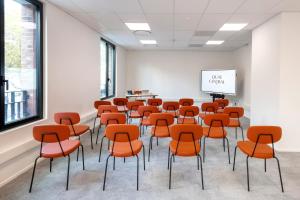 una habitación vacía con sillas naranjas y una pared blanca en Quai Central en Tourcoing