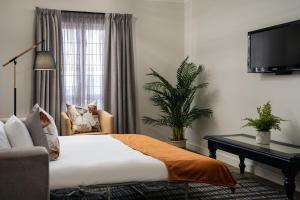 a bedroom with a bed and a chair and a tv at Protea Hotel by Marriott Walvis Bay Indongo in Walvis Bay