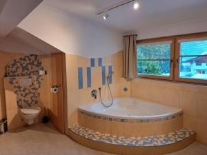bagno con vasca e servizi igienici di Edelweiss Apartments 200m zum Lift - Silvretta Card Premium Inklusive a See