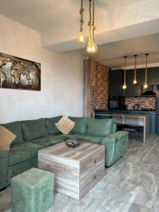 Apartment in Tbilisi,next to metro Sarajishvili Gldani في تبليسي: غرفة معيشة مع أريكة خضراء وطاولة