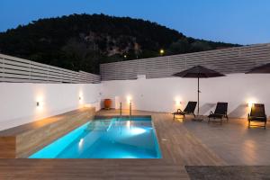 a swimming pool with two chairs and an umbrella at Olea Villa in Archipolis