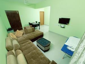 Ananya service apartments في تشيناي: غرفة معيشة مع أريكة وتلفزيون