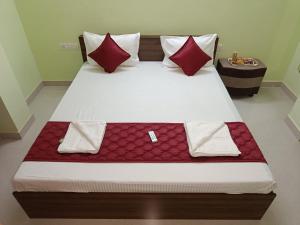 uma cama grande com almofadas vermelhas num quarto em Ananya service apartments em Chennai