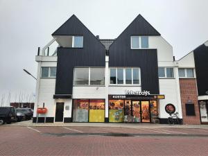 a large black and white building with a store at Bij de Haven op Urk in Urk